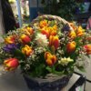 Корзина с желто-оранжевыми тюльпанами и декоративной зеленью